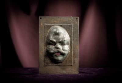 a metal plaque with a picture of a man ' s face on it