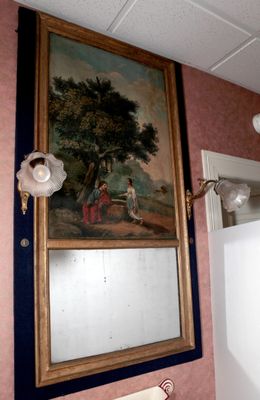un tableau accroché au mur au-dessus d'un miroir dans une salle de bains