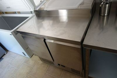 a stainless steel counter top with a trash can in the corner