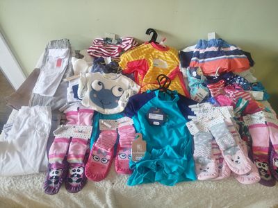 a pile of baby clothes on a bed next to a wall
