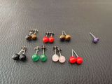 six paires de boucles d'oreilles sont disposées sur une surface noire
