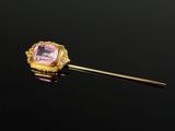 une broche en or et en pierre rose sur un fond noir