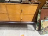 a wooden chest of drawers next to a pile of books