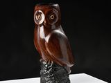 a wooden owl sitting on top of a piece of wood