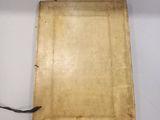an old book is sitting on a white surface with a black cord