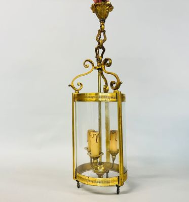 an antique brass and glass lantern with two candles inside of it