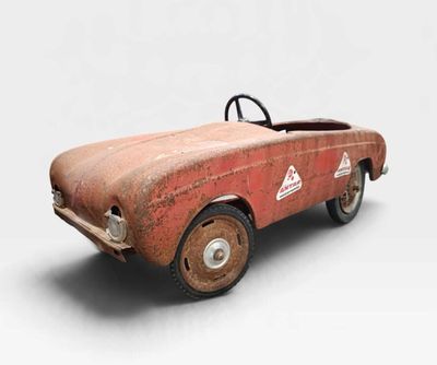 une vieille petite voiture jouet rouillée est posée sur une surface blanche
