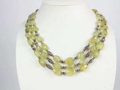 un gros plan d'un collier porté par un mannequin, orné de perles vertes