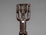 a wooden statue of a man holding a bowl on his head