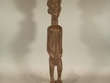 statue of a man standing on a white base with a shadow on the wall behind him