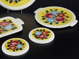 several plates with flowers painted on them sit on a black surface