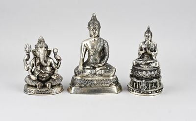 trois figurines en argent représentant des bouddhas sur fond blanc