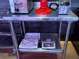 a red coffee maker on a metal table next to a microwave