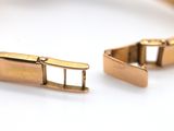 two gold bracelets that are on a white surface