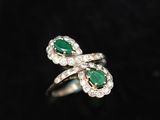 a close up of a ring with a green stone and diamonds