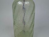 a green glass bottle with a metal faucet on it