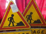 two yellow and red street signs sitting on top of a wooden table