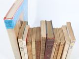 several old books stacked on top of each other on a white surface