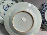 two blue and white plates with gold rims are sitting on a white surface