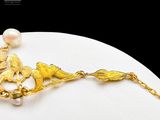 an image of a gold necklace with pearls and a bird