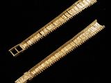 two pieces of gold colored metal bracelets on a black background