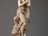 a white marble statue of a woman holding a bird on top of a table