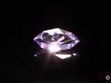 a close up of a purple diamond on a black surface