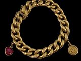 a gold bracelet with a ruby stone charm