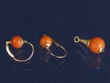 trois paires de boucles d'oreilles en or ornées de perles orange sur un fond noir