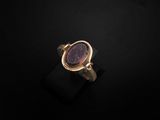 une bague en or avec une pierre violette au centre