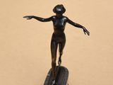 une statue en bronze représentant une femme debout sur une planche de surf