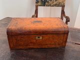 a small wooden box sitting on a table with a chair in the background