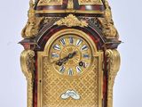 une horloge posée sur un support sur une surface blanche