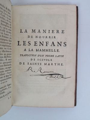 un livre ouvert, sur lequel figure un titre écrit à la main, posé sur une table