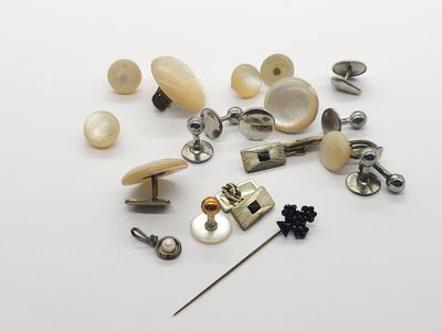 many different types of buttons and pins on a white surface