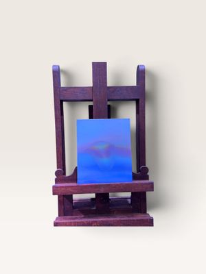 un petit chevalet sur lequel est posé un tableau, posé sur une surface blanche