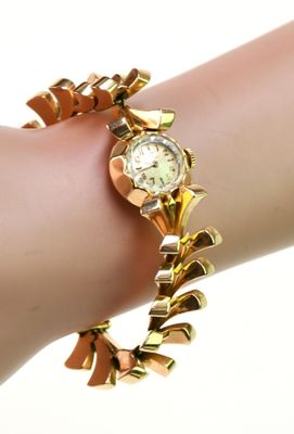 une femme portant un bracelet en or avec une montre au poignet