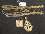 un gros plan sur un collier en or et d'autres bijoux posés sur une surface noire