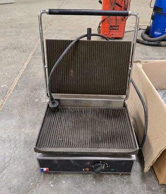 une photo d'un barbecue posé par terre, avec une boîte en arrière-plan