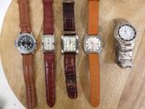 several different watches are sitting on a wooden surface