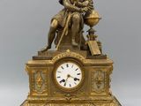 une horloge en or sur laquelle est assis un homme