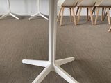 a white table with a black top and four white chairs