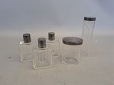 four small glass jars with silver lids are lined up on a white surface