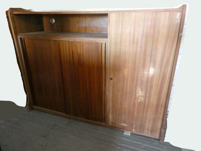 une armoire en bois dont la porte est ouverte, dans une pièce