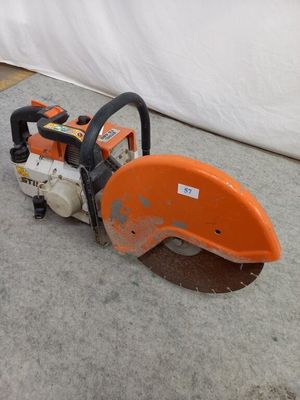 an orange and black chainsaw sitting on the floor next to a white sheet