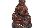 an image of a wooden statue of a man sitting on a stool