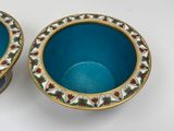 two blue bowls with gold rims on a white surface