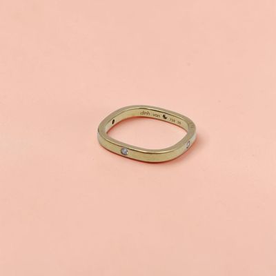 un gros plan d'une bague en or posée sur une surface rose