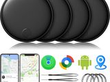 a set of four black gps trackers next to a phone and other gadgets