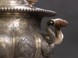 a silver vase that has a handle on it